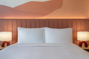 Une chambre d’hôtel avec un grand lit, deux lampes de chevet et un décor mural texturé.