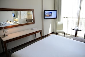 A hotel room with a bed, a desk, a chair, a television, and a window with curtains. - Yas Plaza Circuit by IHG (Abu Dhabi)