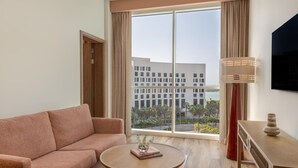 A modern hotel room with a sofa, a round coffee table, a lamp, and a TV. - Yas Plaza Circuit by IHG (Abu Dhabi)