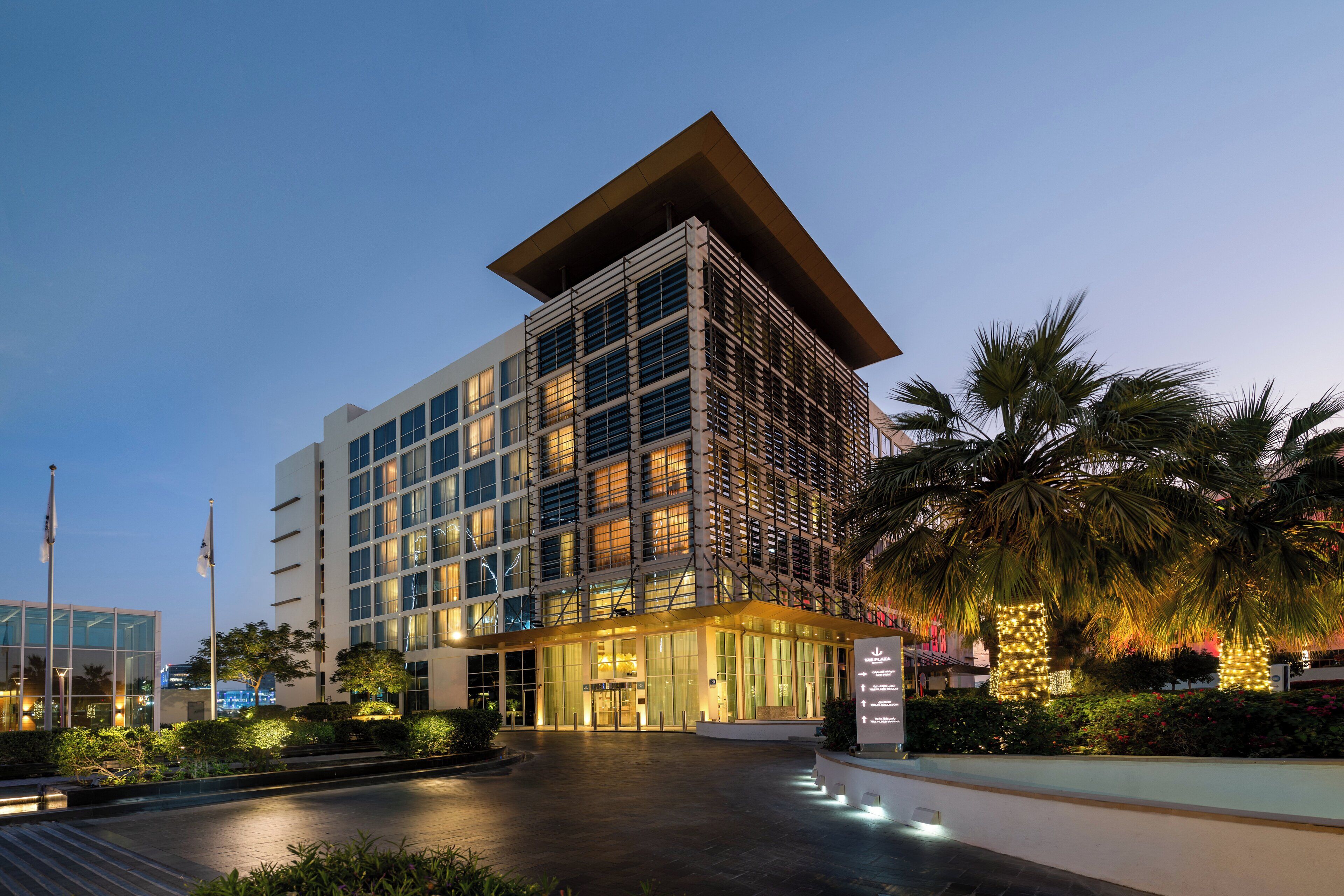 A modern hotel with a prominent corner entrance, large windows, and a well-lit facade.