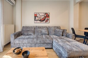 Ein modernes Wohnzimmer mit einem grauen Ecksofa, einem Holztisch und einer schwarzen Schale.