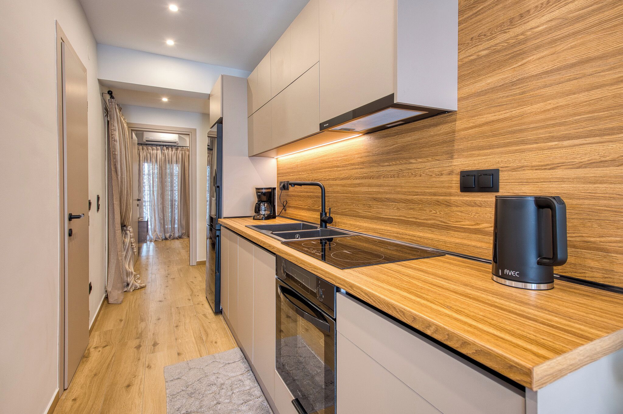 A modern kitchen with a wooden countertop, stainless steel sink, and a coffee maker.