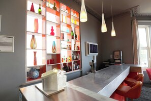 Zona de bar con estantes llenos de botellas y vasos, barra y asientos.