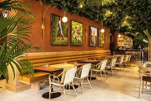A restaurant with wooden booths, wicker chairs, and a bar area. - Verno House Budapest, Vignette Collection, an IHG Hotel (Budapest)