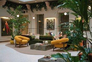 Una sala de estar moderna con un sofá verde, sillones amarillos y una mesa de centro de mármol.