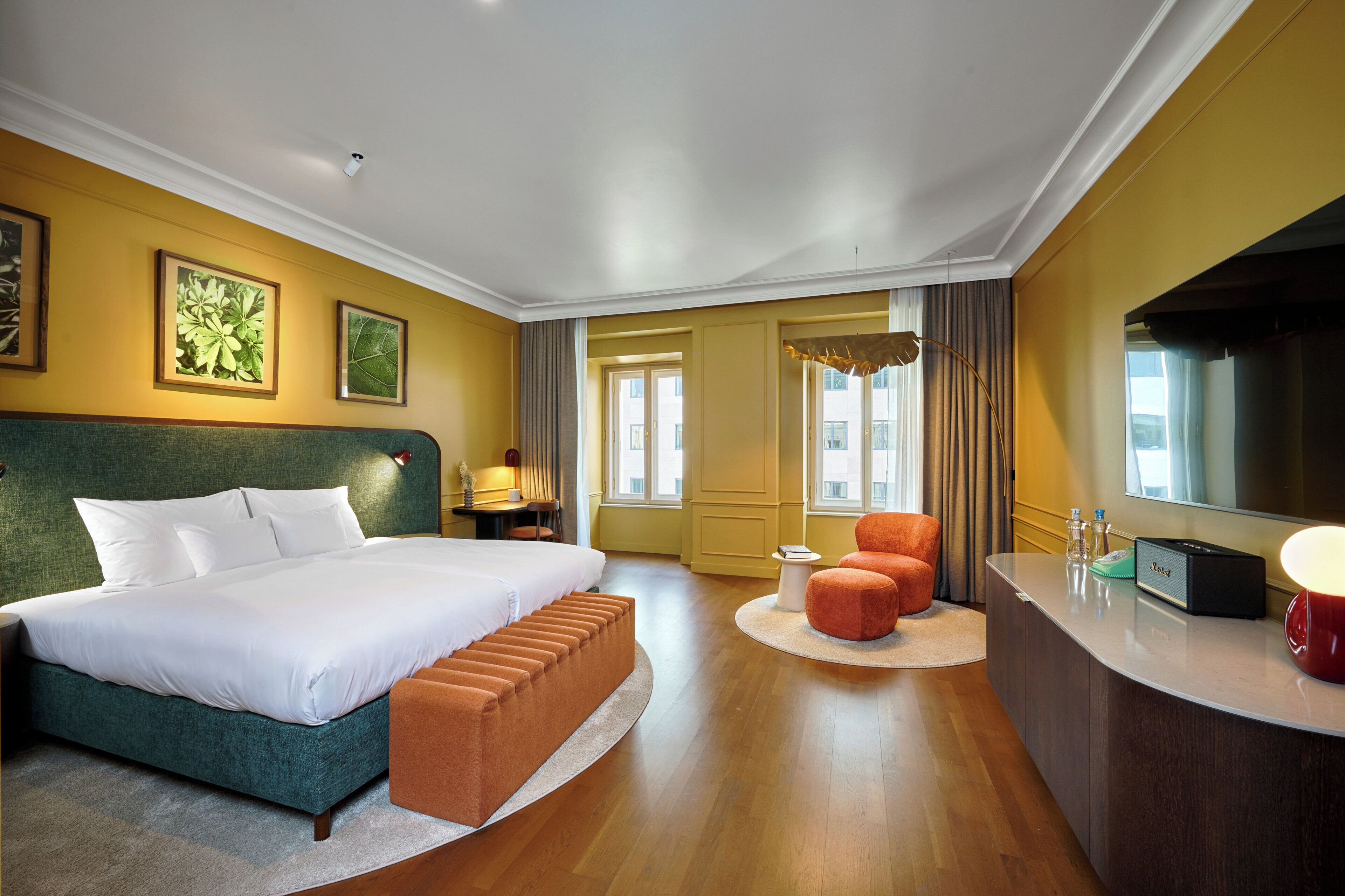 A hotel room with a large bed, a desk, a chair, and a television.