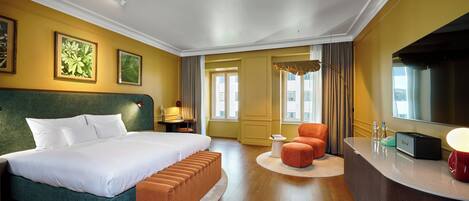 A hotel room with a large bed, a desk, a chair, and a television.