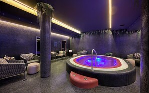 Área de spa com hidromassagem, assentos e plantas decorativas.