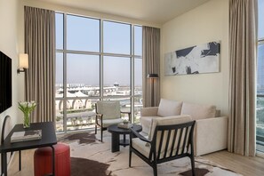 A modern living room with a large window, a sofa, a chair, a small table, and a lamp. - Yas Plaza Marina by IHG (Abu Dhabi)