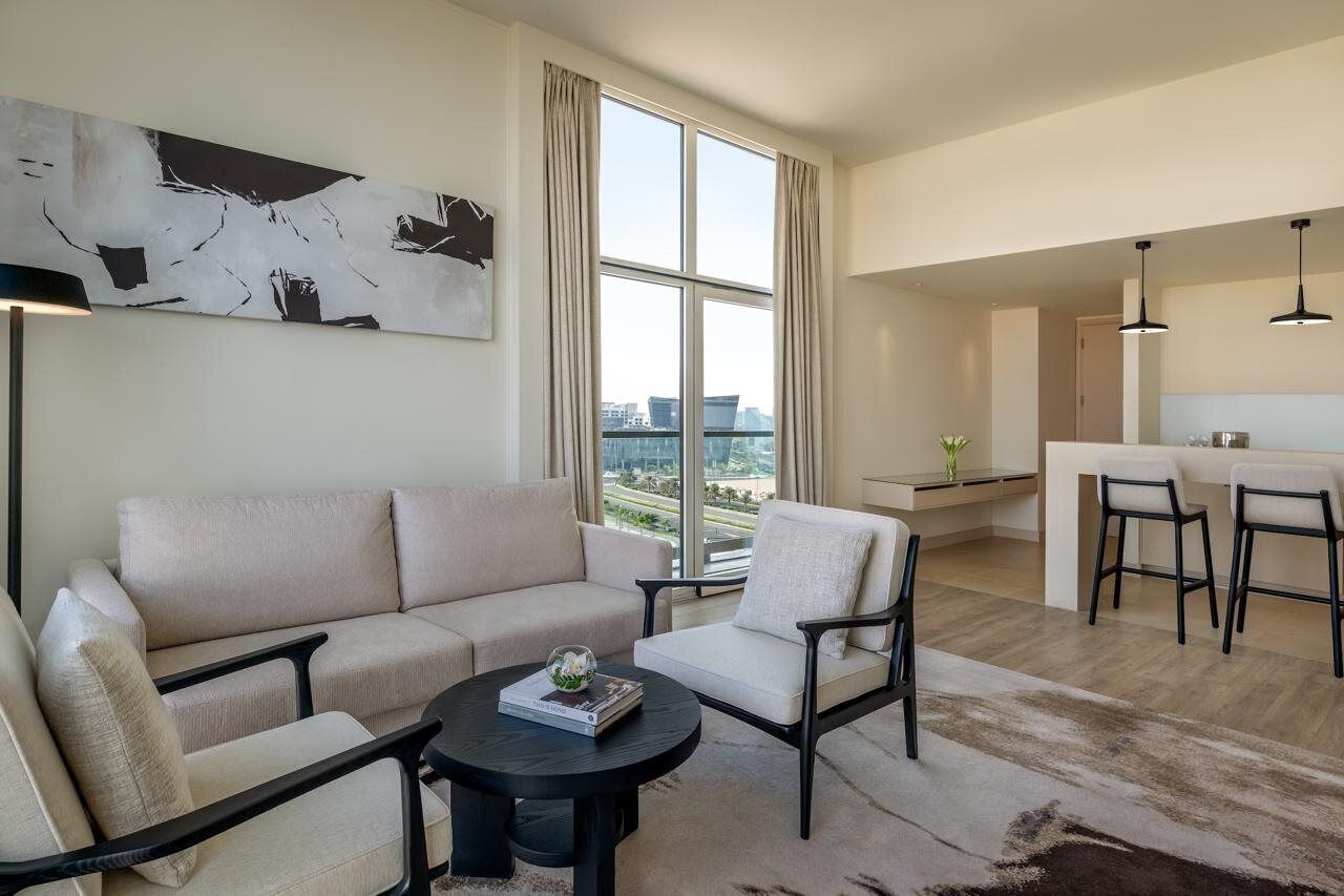 A modern living room with a sofa, armchairs, a coffee table, and a large abstract painting.