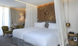 A hotel room with a large bed, a green armchair, a bedside table with a lamp, and a wooden accent wall. - Sofitel Marrakech Palais Imperial and Spa (Marrakech)