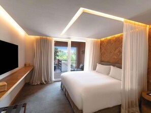A hotel room with a large bed, a TV on a wooden shelf, a balcony with curtains, and a patterned wall. - Sofitel Marrakech Palais Imperial and Spa (Marrakech)
