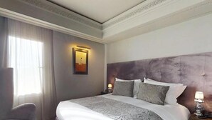 Een hotelkamer met een groot bed, een stoel, een nachtkastje en een schilderij aan de muur.