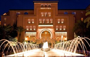 A hotel with a prominent arched entrance, a fountain in front, and palm trees around. - Sofitel Marrakech Palais Imperial and Spa (Marrakech)