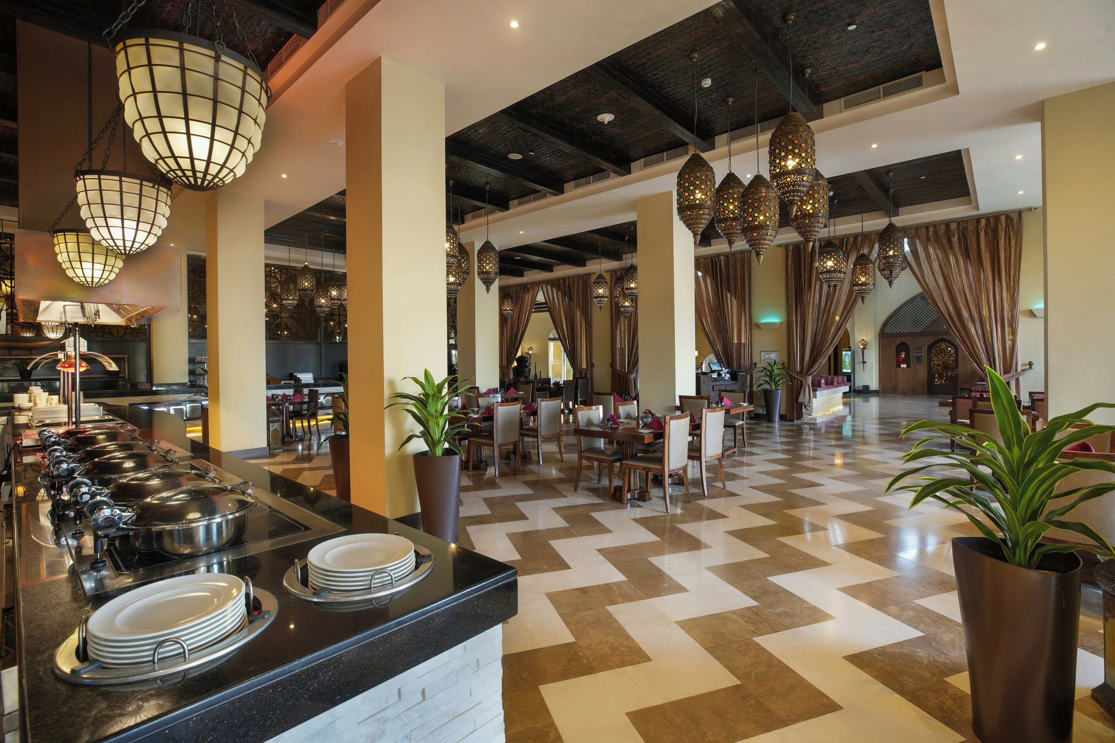 A hotel lobby with a buffet area, dining tables, and a check-in desk.