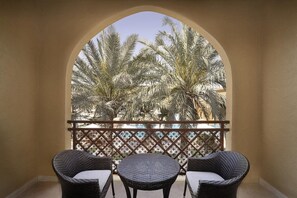 A balcony with a wrought iron railing, two wicker chairs, and a small round table. - Aldhafra Resort, Vignette Collection, an IHG Hotel (Madinat Zayed)