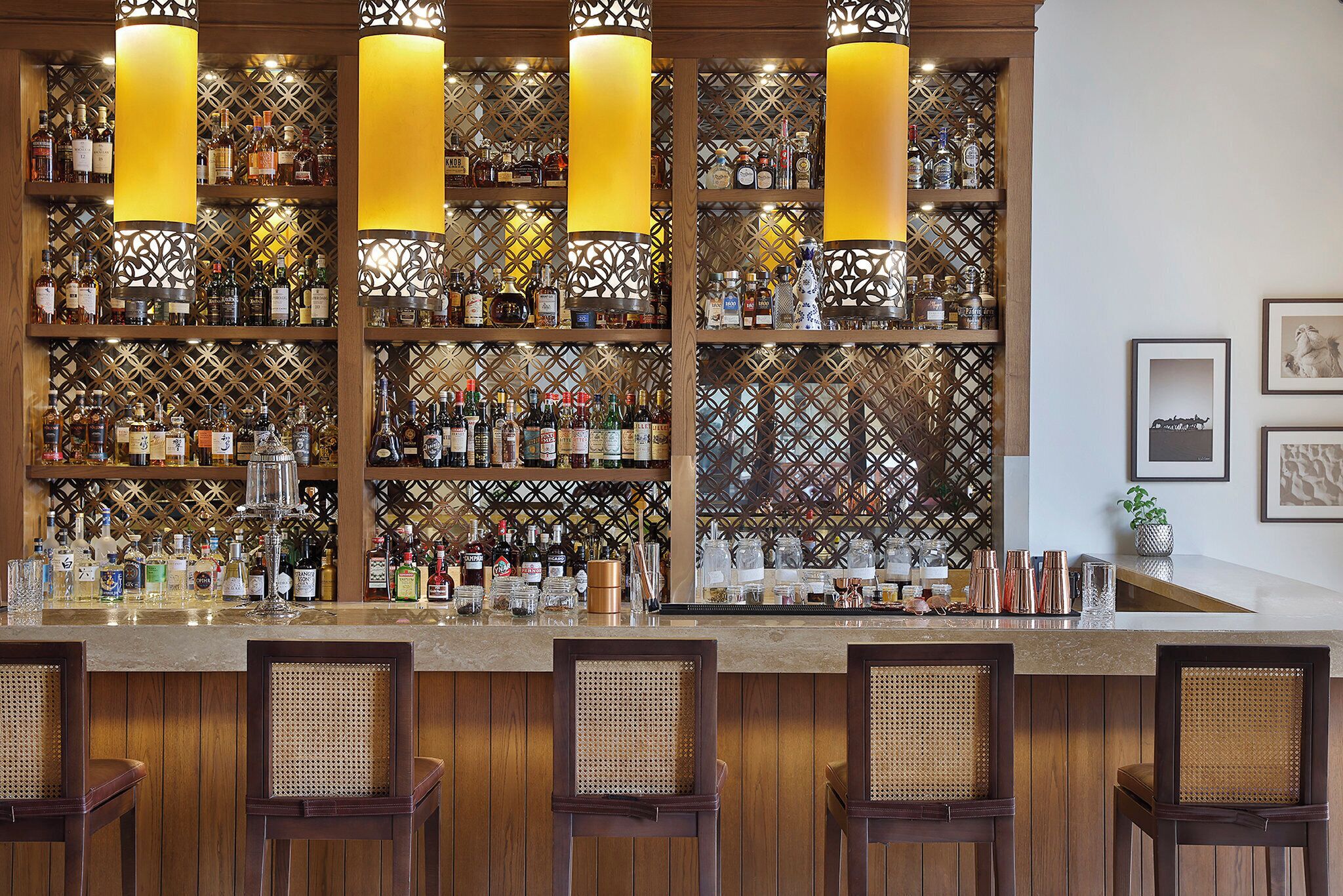 A bar area with wooden paneling, multiple liquor bottles, and bar stools.