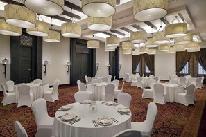 A banquet hall with round tables set for dining, white chairs, and hanging pendant lights. - Aldhafra Resort, Vignette Collection, an IHG Hotel (Madinat Zayed)