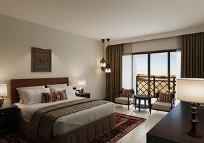 Una habitació d'hotel amb un llit gran, una taula de treball amb una cadira, un balcó amb vistes al desert i una peça decorativa a la paret.