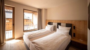Une chambre avec deux lits, des têtes de lit en bois et une grande fenêtre.