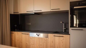 Une cuisine moderne avec des meubles en bois, un plan de travail noir et un four encastré.