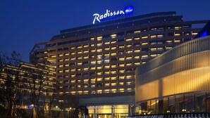 Un hôtel Radisson doté d’une façade moderne, de plusieurs étages et d’une cour intérieure agrémentée d’un élément décoratif aquatique.