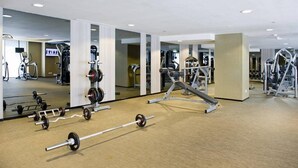 A gym with various exercise equipment, mirrors, and a carpeted floor.