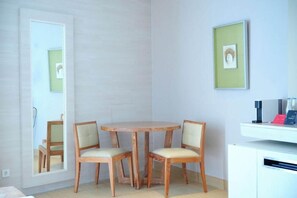 A room with a round wooden table, two chairs, a white cabinet, and a framed picture on the wall. - The Stones Hotel Legian Bali Autograph Collection (Legian)