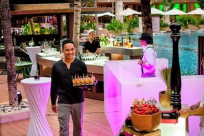 A bar area with a pool, bar stools, and a bartender. - The Stones Hotel Legian Bali Autograph Collection (Legian)