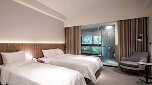 A hotel room with two beds, a seating area, and a glass door leading to a balcony. - Guan Xiang Century Hot Spring Hotel (Jiaoxi)