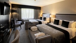 Habitación de hotel con dos camas, un sofá, un televisor y un escritorio.