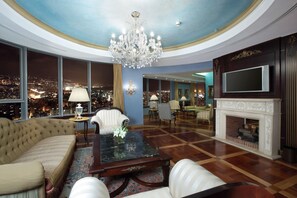 A spacious living room with a large chandelier, a fireplace, and a city view through large windows. - Al Habtoor Grand Hotel Beirut (Sin El Fil)