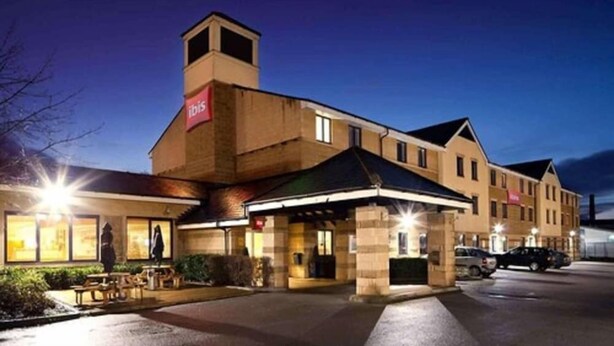 Un hotel con una entrada llamativa, un espacio al aire libre cubierto y un estacionamiento.