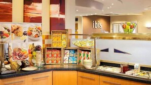 Zona de bufé con diferentes opciones de comida y un cartel que dice 'ibis'.