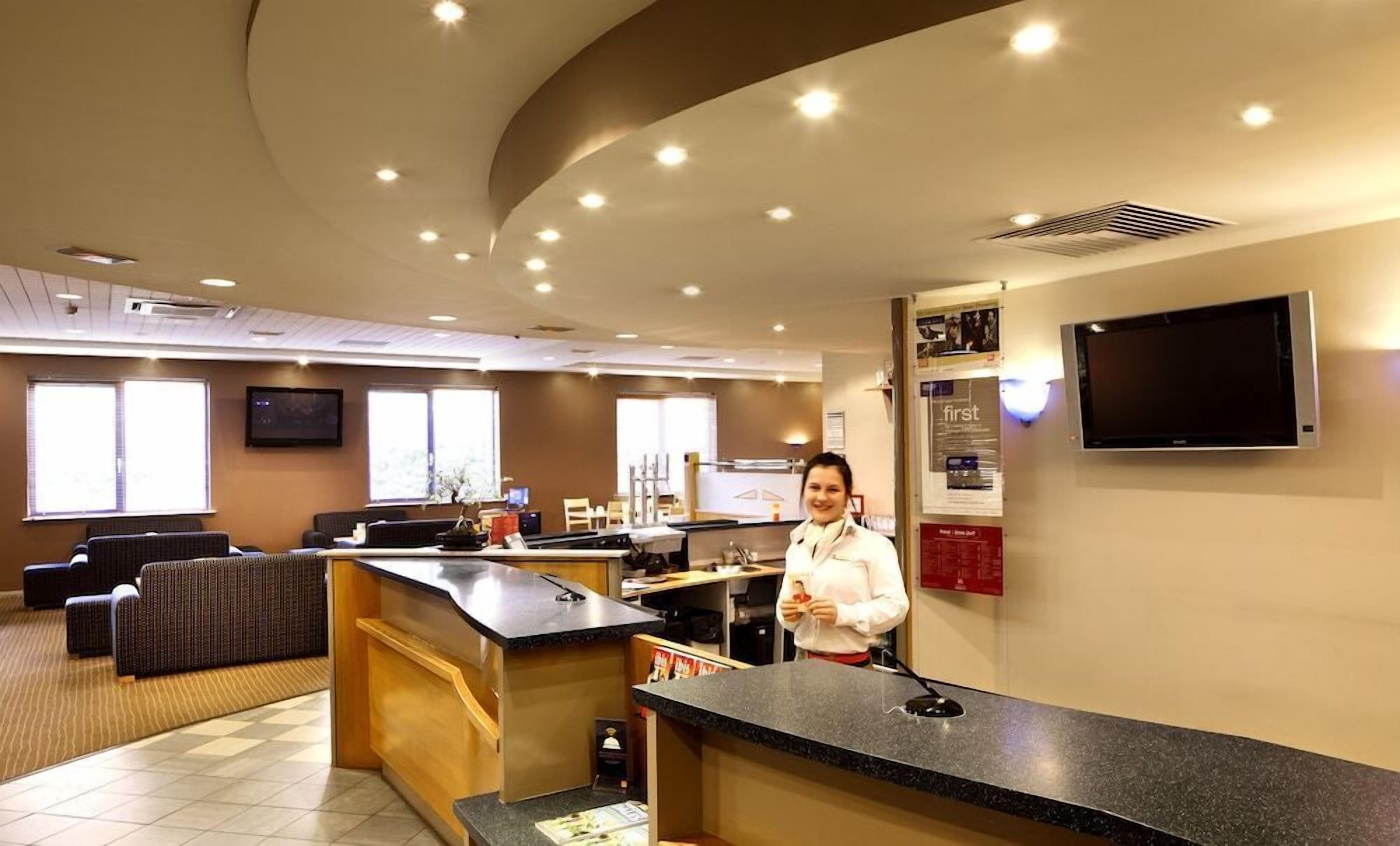 A hotel reception area with a counter, seating, and a television.