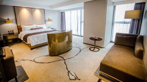 Una habitación de hotel moderna con cama, zona de estar, escritorio y vistas a la ciudad.