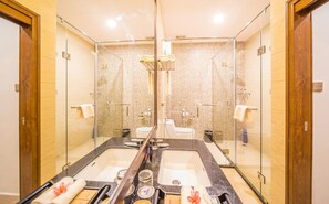 Een badkamer met een grote spiegel, twee wasbakken en een douchegedeelte.