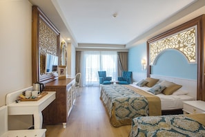 Camera d'albergo con un letto, due poltrone, una scrivania, un comò e uno specchio grande.