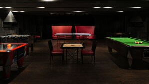 A dimly lit room with a pool table, red seating, and a foosball table. - Taj Alibaug Resort & Spa, Maharashtra (Alibag)