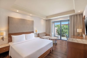A hotel room with a large bed, a sofa, a small table, a desk, and a TV. - Taj Alibaug Resort & Spa, Maharashtra (Alibag)