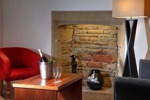 Un saló acollidor amb una llar de pedra, un sofà vermell, una taula de centre de fusta i una làmpada de peu.