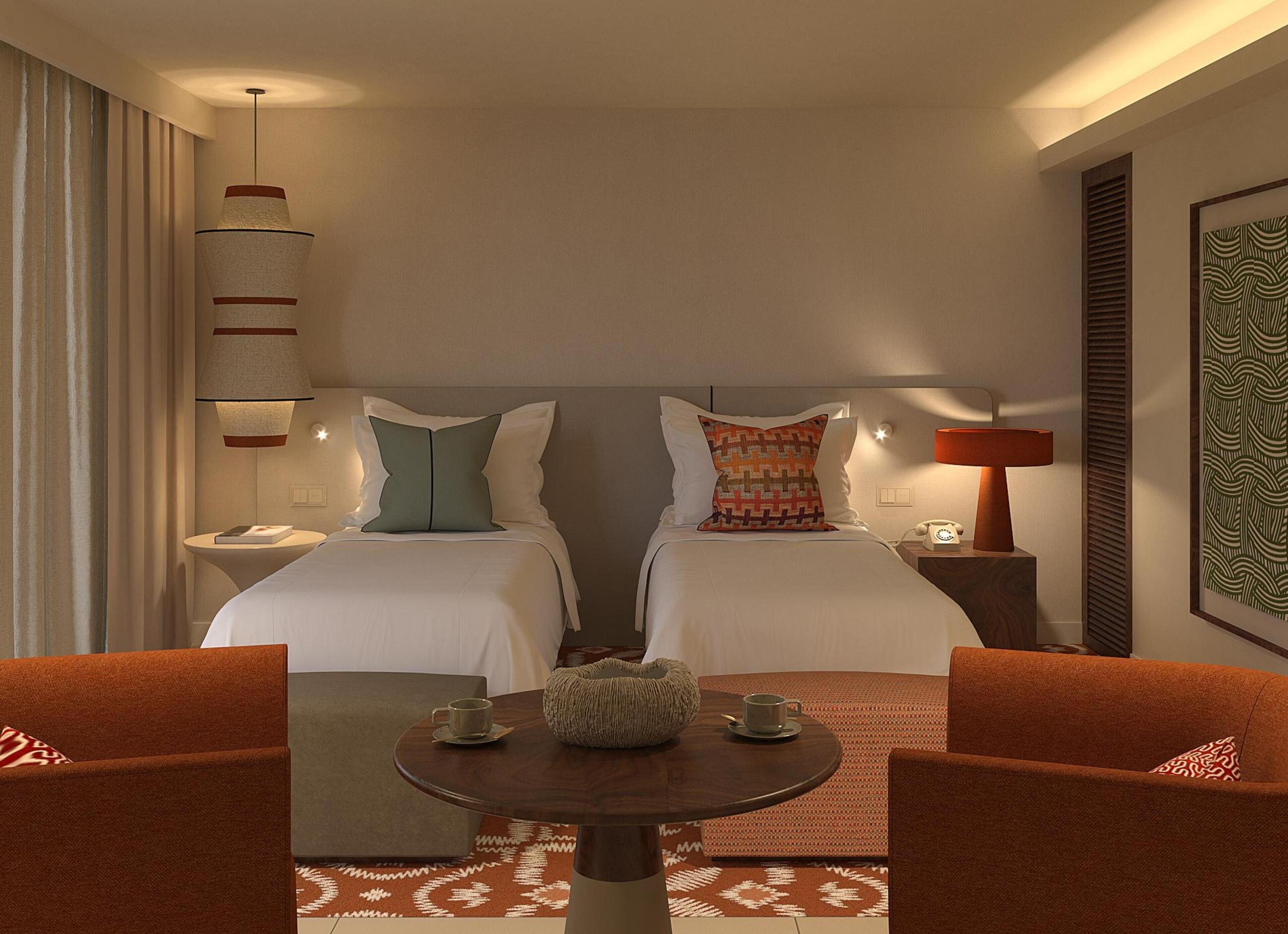 Een hotelkamer met twee bedden, een ronde tafel met stoelen, een lamp en een telefoon op het nachtkastje.