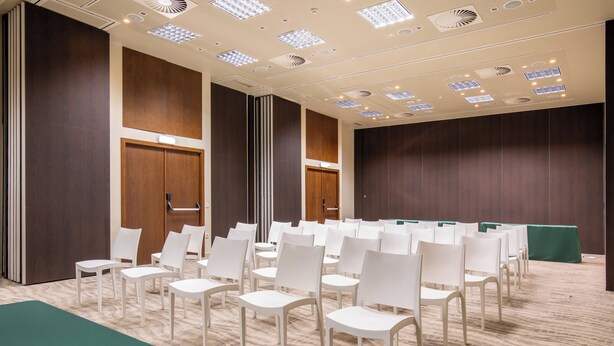 A conference room with rows of white chairs, wooden panel walls, and recessed ceiling lights. - Kimpton Atlântico Algarve, an IHG Hotel (Albufeira)