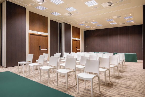 A conference room with rows of white chairs, wooden panel walls, and recessed ceiling lights. - Kimpton Atlântico Algarve, an IHG Hotel (Albufeira)