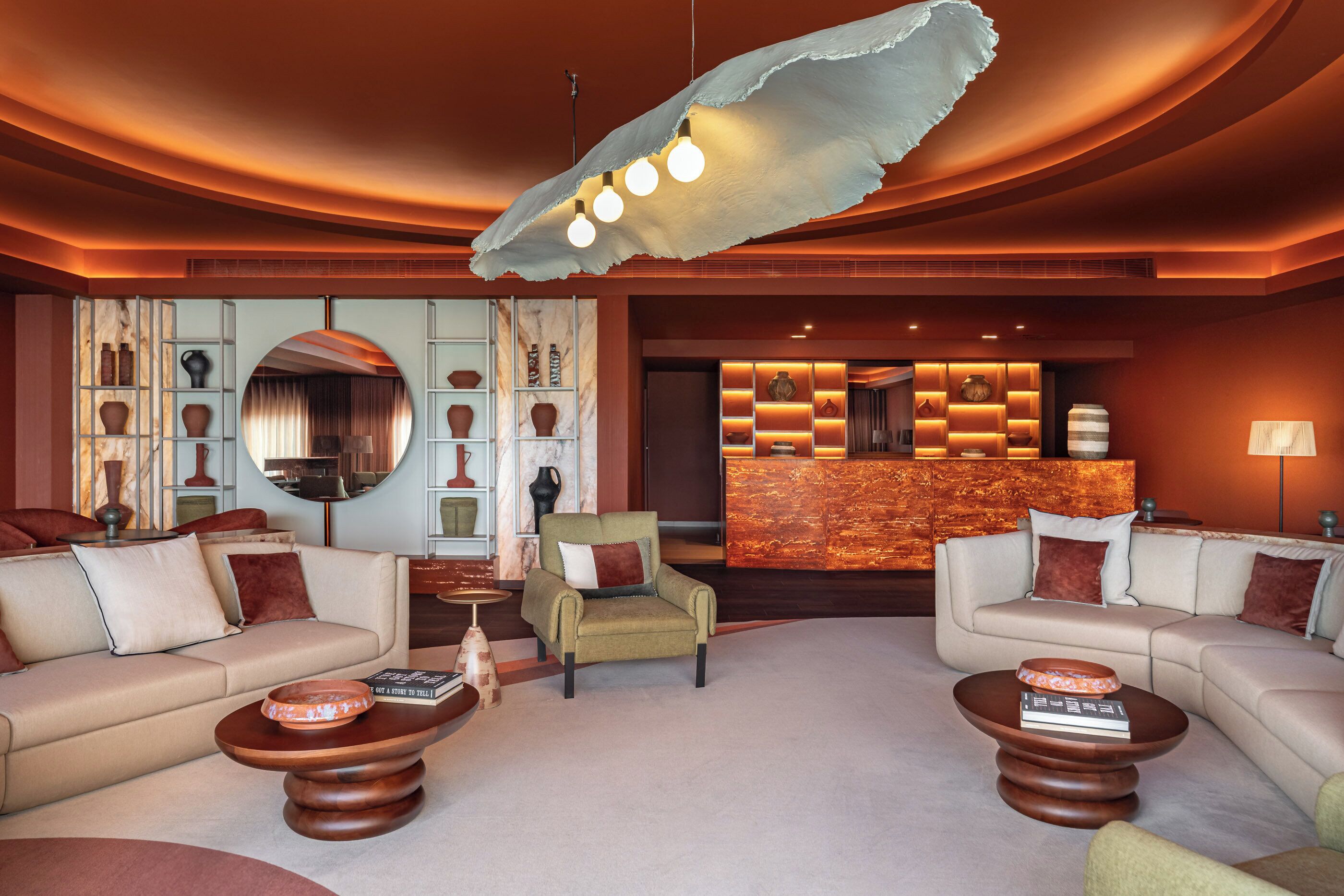 Een moderne lobby met banken, een receptiebalie en decoratieve elementen zoals vazen en een spiegel.