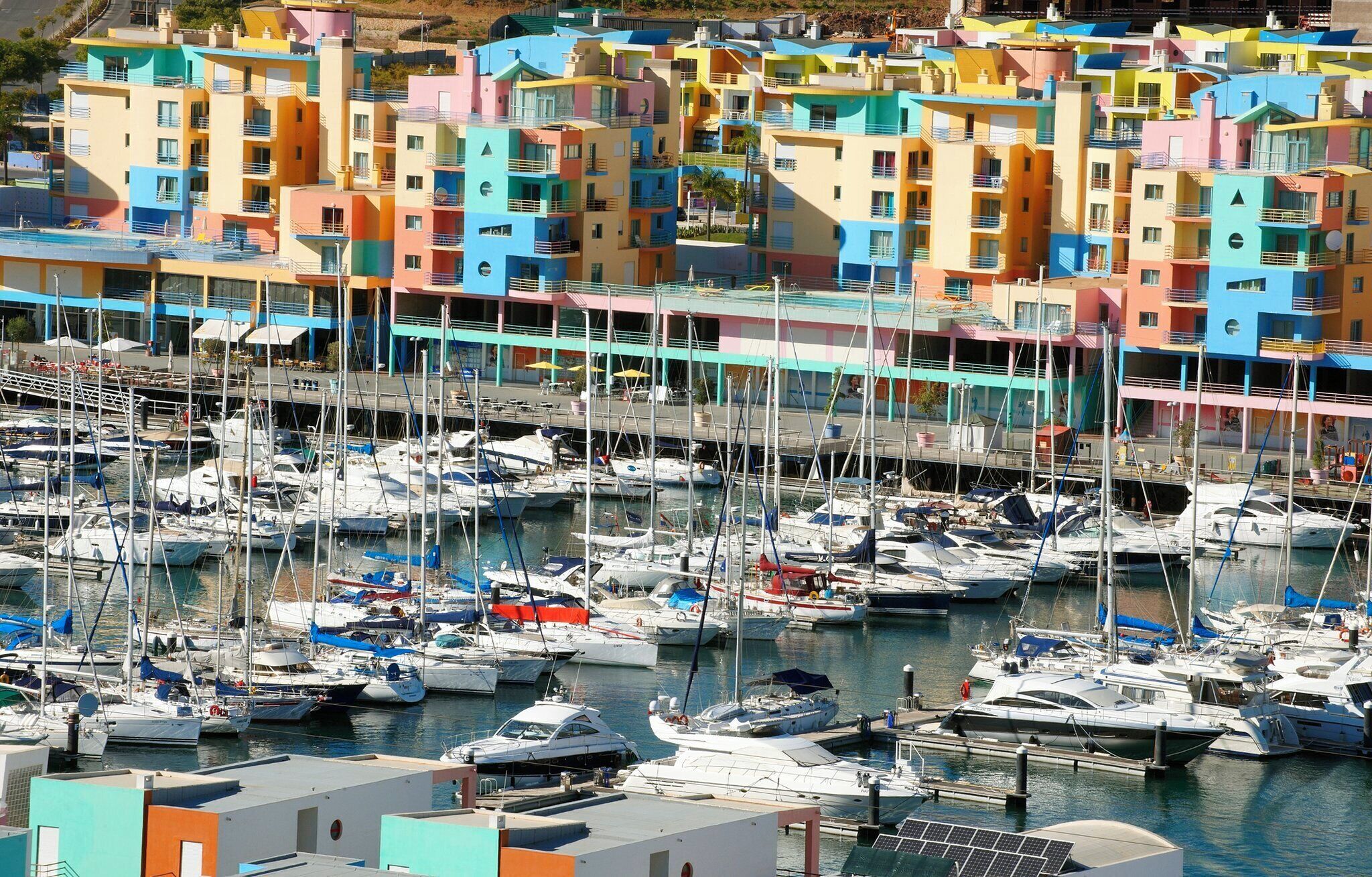 A marina with colorful buildings and numerous boats docked.