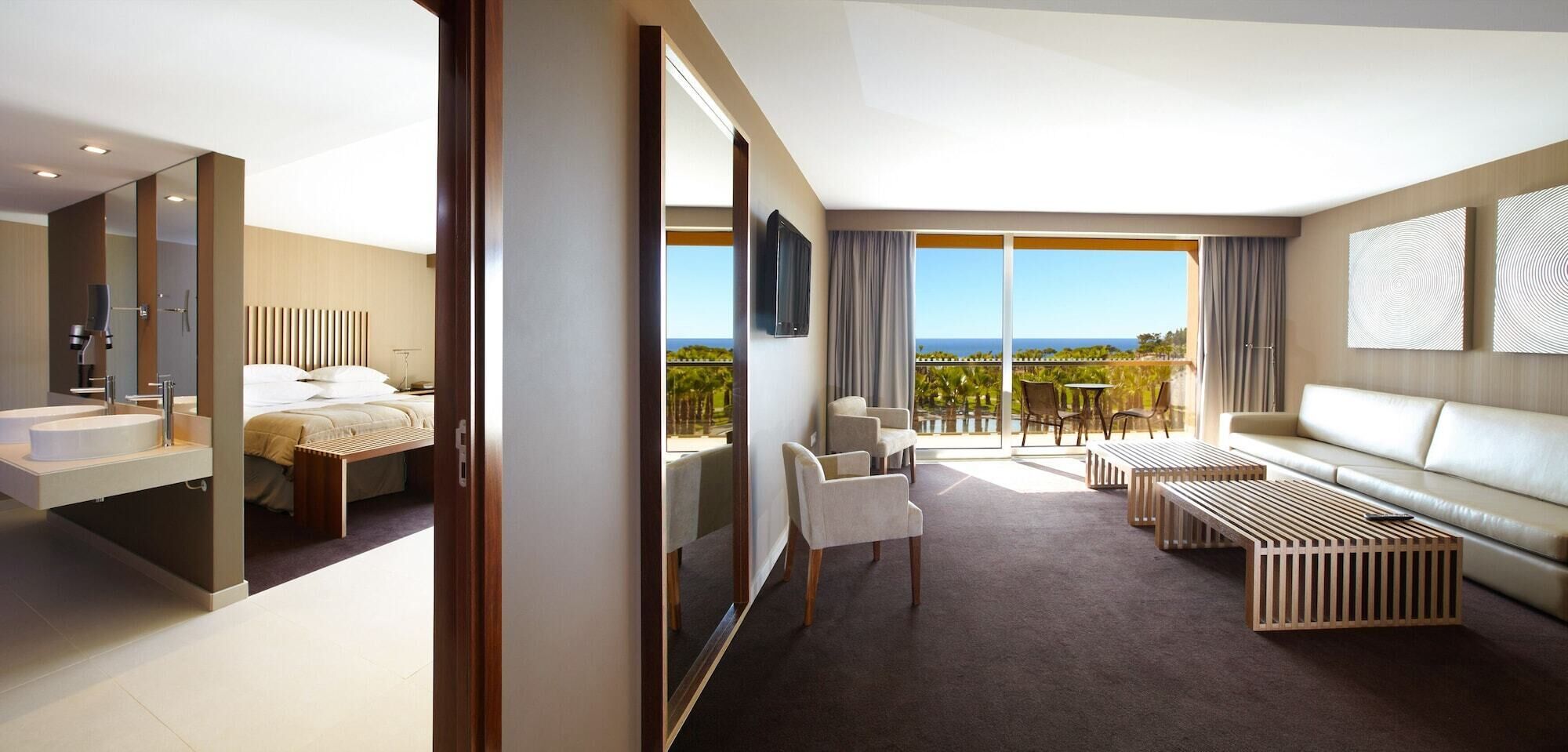 Een moderne hotelkamer met balkon, een bank, een koffietafeltje en een bed.
