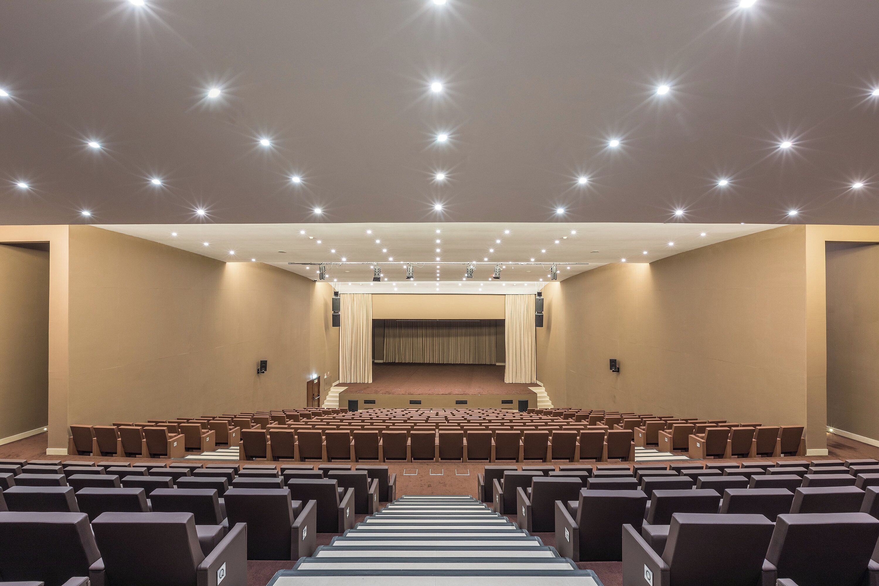 A large, well-lit auditorium with rows of seats and a stage at the front.