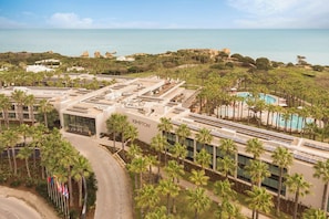 A hotel with a rooftop pool, palm trees, and a view of the sea. - Kimpton Atlântico Algarve, an IHG Hotel (Albufeira)