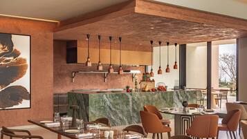 A modern dining area with a marble island, wooden chairs, and pendant lighting.